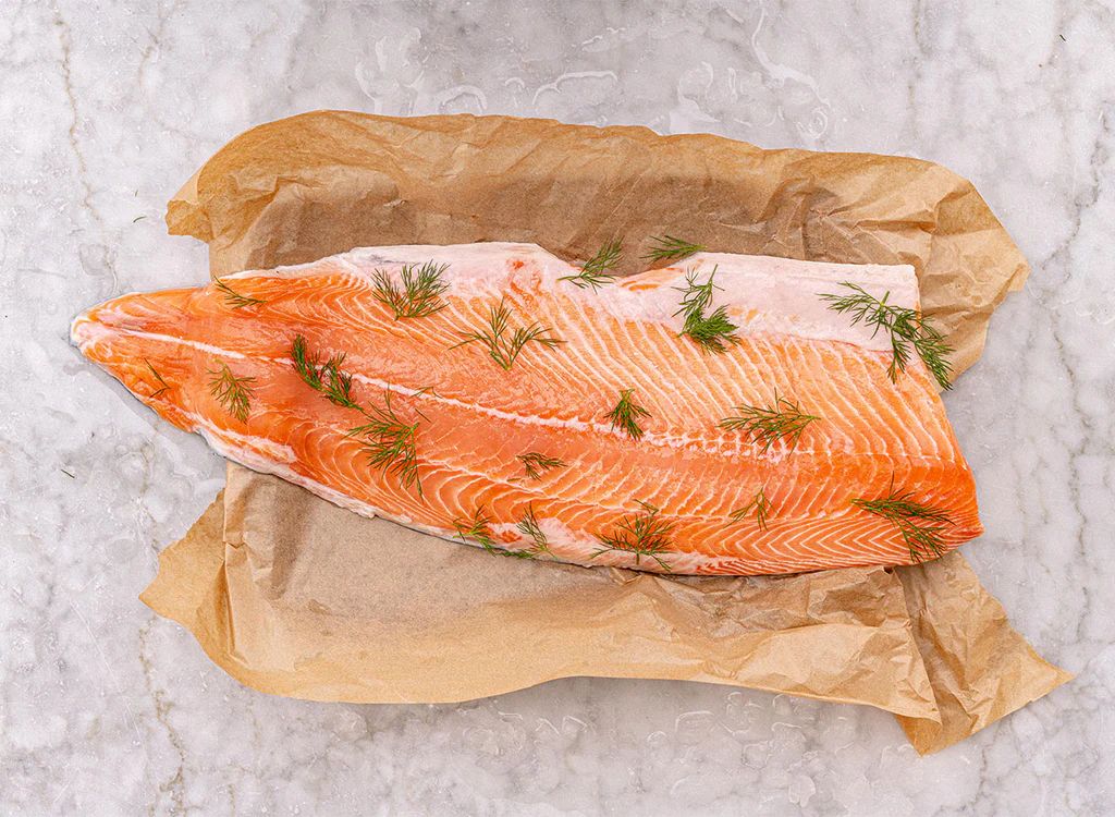 Raw salmon fillet on brown paper with dill on a marble surface